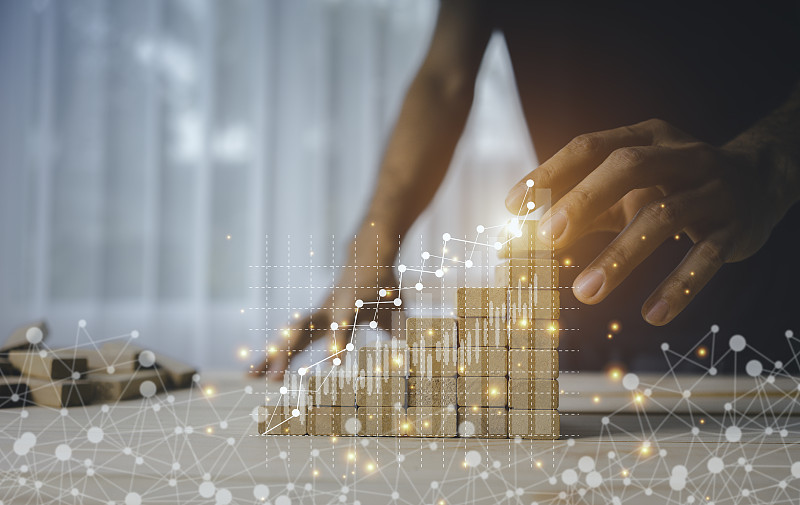 一位女商人的手正在沿着上升的图形排列木制玩具。业务成长成功过程的概念图片下载