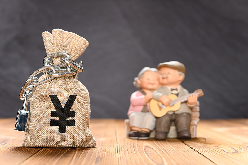 铁链锁住的人民币钱袋子及虚化的快乐老两口图片下载